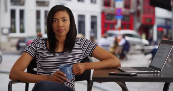 描述了一个在户外喝咖啡休息的黑人女商人 在笔记本电脑上工作的非裔美国女性对着相机微笑 — 图库视频影像