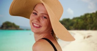 Virgin Adaları, St John 'da güzel bir plajda duran yumuşak şapkalı mutlu milenyum kadını. Tropikal okyanusa bakan bir turist. 20 'li yaşlarda, güneş şapkalı ve siyah mayosu olan bir kadın. 4k