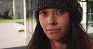 Bere takan bin yıllık bir kadının okul çıkışında kamerayla göz teması kurarken çekilmiş yakın bir portresi. Saçları rüzgarda savrulan beyaz bir kızın lenslere bakarken çekilmiş fotoğrafı. 4k