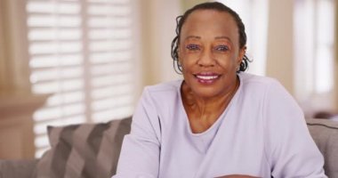 Yaşlı siyah bir kadın kameraya mutlu bir şekilde bakıyor. Yaşlı bir Afrikalı Amerikalı kadın neşeyle bir portre için poz veriyor. 4k
