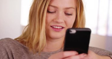 Akıllı telefon cihazı kullanan mavi gözlü güzel sarışın milenyum kadınının yakın plan portresi. Güzel bir kızın cep telefonuyla mesaj attığı yakın plan. 4k