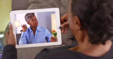 Yaşlı siyahi bir kadın arkadaşıyla görüntülü sohbet yoluyla konuşuyor. Yaşlı siyah bir kadın tabletinde kız arkadaşıyla konuşuyor. 4k