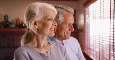 Pencereden dışarı bakan mutlu yaşlı çiftin yakın çekimi. Gülümseyen yaşlı çiftin profil portresi. 4k