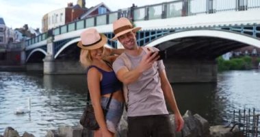 Windsor 'da selfie çeken seksi genç çift. Mutlu ve çekici çift Windsor Köprüsü 'nün yakınında bir fotoğraf için poz veriyor. 4k