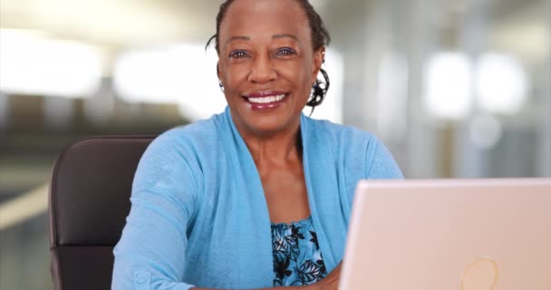 アフリカ系アメリカ人の女性は仕事でコンピュータを喜んで使う 黒人のビジネスマンは彼女の机の上で彼女のラップトップを使う — ストック動画