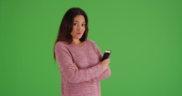 身穿粉色毛衣 手持手机在绿色屏幕上摆姿势的古巴女性画像 在绿色屏幕上键入或合成 — 图库视频影像