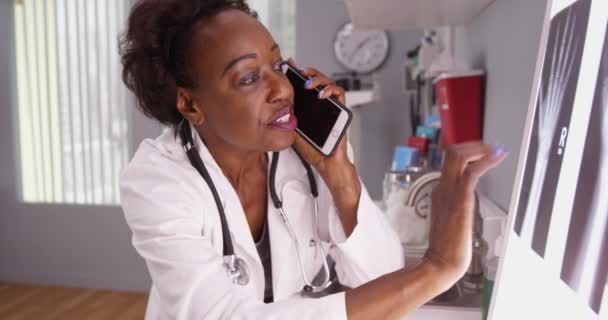 非洲女医生与同事通过电话通过X光进行交流的肖像 黑人放射学家在手机上与病人谈论他们的X光检查 — 图库视频影像