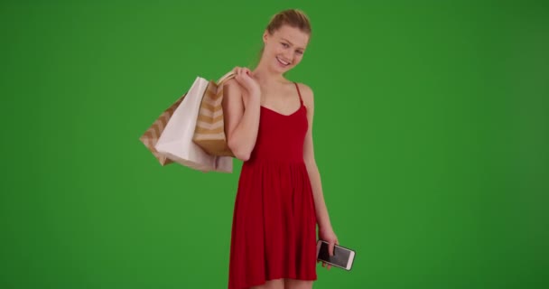 緑の画面上の肩の上にショッピングバッグと赤いドレスで美しい幸せな若い白人女性 緑の画面でキーまたは構成されます — ストック動画