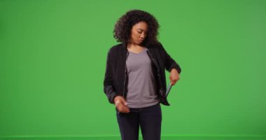 Kadın ekranda yürüyor cep telefonunu kontrol ediyor sonra da yeşil ekrandan çıkıyor. Bombacı ceketi giyen siyah milenyum kızı anahtarlama veya birleştirme için yeşil arka planda kısa mesajlar alıyor. 4k