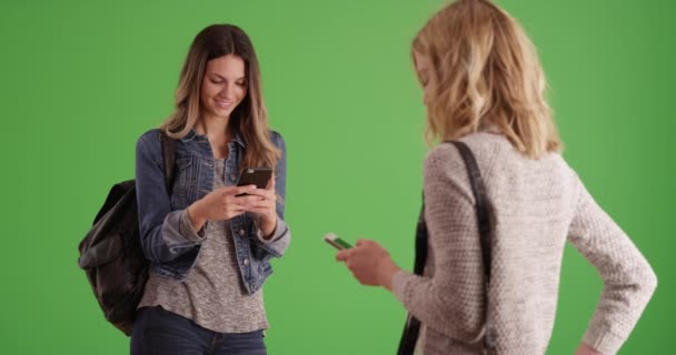 Dwie Studentki Stoją Smsują Smartfonach Pozowanych Zielonym Ekranie Para Pięknej — Wideo stockowe