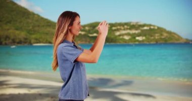 Çekici bir milenyum kızının plajda cep telefonuyla fotoğraf çektiği profil. Yazın tatildeyken okyanus manzarasını fotoğraflayan beyaz bir kadının profili. 4k
