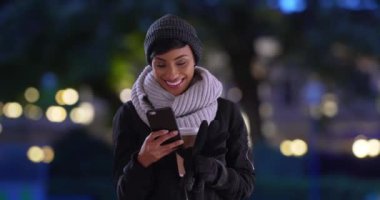 Cep telefonu kullanarak bir fincan sıcak kahve içen genç ve güzel bir kadın. Şapkalı ve fularlı bir kadının portresi telefonda kısa mesaj okuyor. 4k