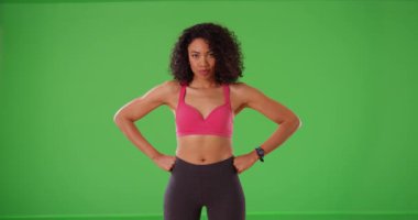 Yeşil ekranda gülümseyen ve gülen güçlü siyah kadın sporcu. Genç ve mutlu bayan fitness eğitmeni yeşil ekranda gülümser ve güler. 4k