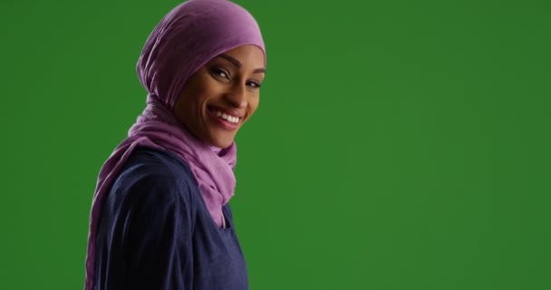 穿着紫色头巾的美丽的年轻黑人妇女 在绿色的屏幕上对着相机微笑 在绿色屏幕上键入或合成 — 图库视频影像