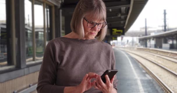 Allvarlig Senior Kvinna Med Telefon Mottagning Angående Nyheter Medan Tågstationen — Stockvideo