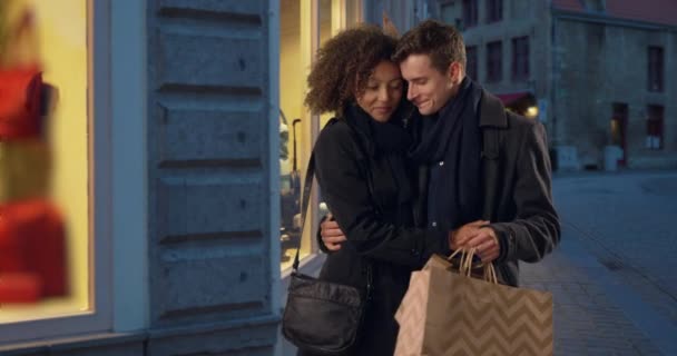 年轻而快乐的夫妻傍晚在布鲁日购物的画像 迷人的白人男性和非洲女性拿着购物袋 — 图库视频影像