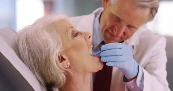 의사가 노부인의 치아를 진찰하고 시니어 의사가 시녀의 이빨을 검사하고 — 비디오