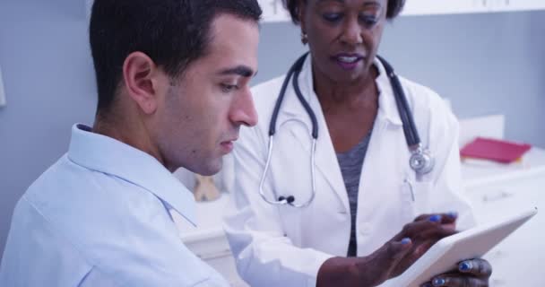 黑色高级医生的肖像 用笔记本平板显示病人的测试结果 在手提式电子垫子上看考试成绩的年轻男性拉丁裔病人的近视 — 图库视频影像