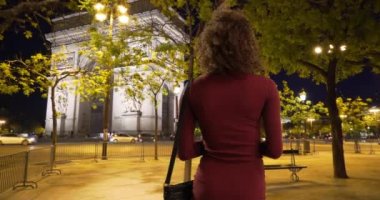 Güzel siyah kadın akşamları Zafer Takı 'na hayran oluyor. Geceleyin Paris caddesinde duran bin yıllık kadının dikiz görüntüsü. 4k