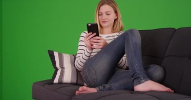 Genç milenyumun portresi, yeşil ekranda cep telefonu okuyarak koltukta dinleniyor. Anahtar ya da birleşik olmak üzere yeşil ekranda.