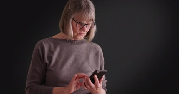 Seriös Senior Kvinna Använder Smartphone För Att Läsa Dagens Tragiska — Stockvideo