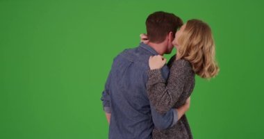 Arkasından kucaklaşan ve yeşil ekranda sevgi dolu davranan mutlu evli çift. Anahtar ya da birleşik olmak üzere yeşil üzerine.