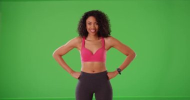 Yeşil ekranda gülümseyen ve gülen atletik siyah kadın antrenör. Genç ve mutlu bayan fitness eğitmeni yeşil ekranda gülümser ve güler. 4k