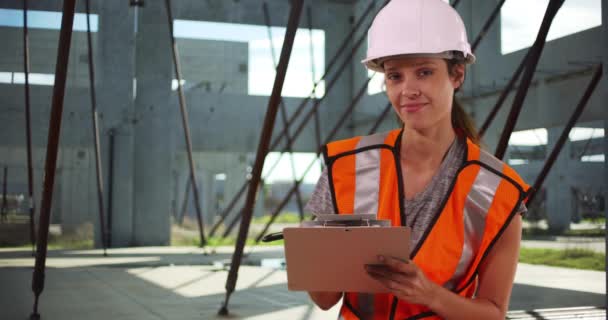 Trabajadora Construcción Chaleco Chaleco Seguridad Haciendo Notas Portapapeles Sonriendo Cámara — Vídeos de Stock