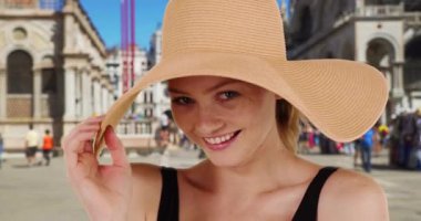 St. Mark Meydanı 'nda mutlu ve şık bir kadın turist. Yılbaşı kızı, kameraya gülümseyen yumuşak güneş şapkası modelliği yapıyor. 4k
