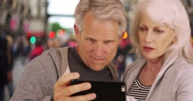 Olgun bir çift Londra 'da yol tarifi hakkında tartışıyor. Cep telefonunda harita kullanan kadın ve erkeğe yakın çekim. 4k