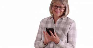 Beyaz fotokopi uzayındaki birine mesaj atmak için telefonu kullanan neşeli, olgun bir beyaz kadın. Beyaz arka planda cep telefonuyla mesajlaşan mutlu son sınıf öğrencisi. 4k