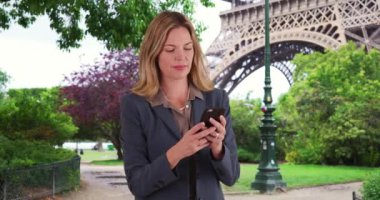 Paris 'li iş kadını cep telefonuyla mesajlaşıyor. İş e-postalarına cep telefonuyla cevap veren beyaz bir kadının gülümseyen portresi. 4k