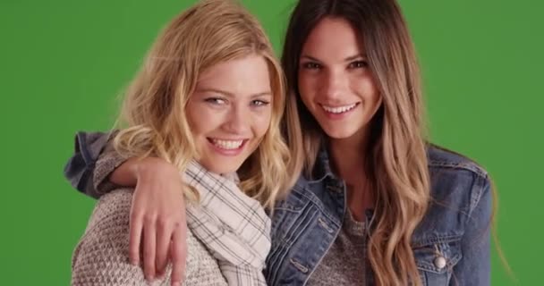 一对年轻貌美的女人互相微笑着在绿屏上摆姿势拍照 在绿色荧幕上 两个漂亮的女友紧紧拥抱在一起 彼此都很快乐 — 图库视频影像