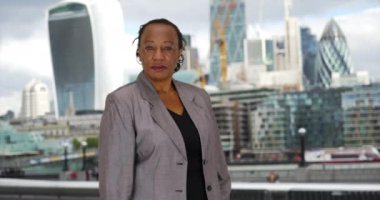 Olgun ofis çalışanı, Londra şehir merkezinde portre için poz veriyor. İş elbisesi giymiş Afrikalı bir Amerikalı kadın şehirdeki kameraya gülümsüyor. 4k