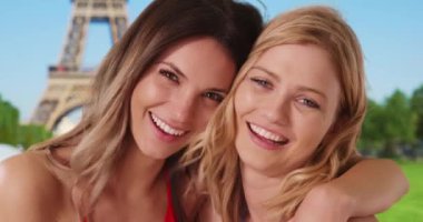 Paris 'te Eyfel Kulesi' nin önünde birlikte poz veren iki beyaz kadın. Paris 'te seyahat eden, Fransa' da gülümseyen ve birbirine sarılan iki kankayız. 4k