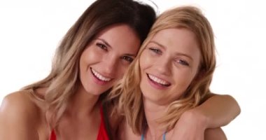 Beyaz fotokopi alanında mutlu bir şekilde poz veren iki genç beyaz kadının portresi. Sarışın arkadaşı beyaz arka planda duran çekici bir esmer. 4k