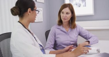 Orta yaşlı beyaz bir hastanın portresi. Doktorun muayenehanesinde genç doktorla sağlık hakkında konuşuyor. Sağlıklı yaşlı bir kadın, genç ve zeki bir kadın doktorla konuşuyor.