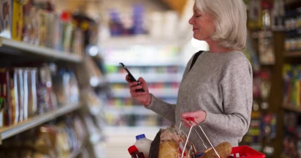 Mujer Mayor Feliz Mirando Pasillo Tienda Comestibles Con Teléfono Celular — Vídeo de stock