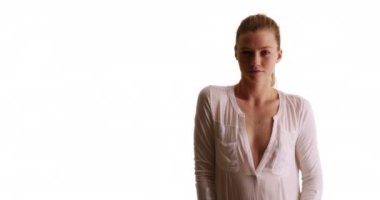 Güzel bir kadın kameraya bakıyor ve arka planda beyaz gömlekle oynuyor. Blonde Millennial stüdyoda arka planda, kopyalanmış. 20 'li yaşlarda boynu açık bir kız. 4k