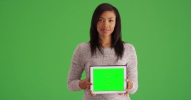 Özel içerik için yeşil ekranlı tablet tutan mutlu zenci kadın portresi. Stüdyoda yeşil ekranlı boş bilgisayar gösteren sevimli Afrikalı Amerikalı kadın milenyumu. 4k