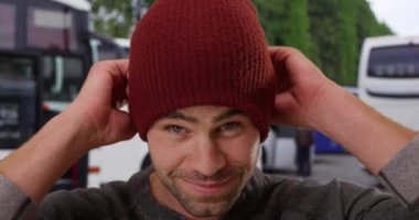 Dışarıdaki seksi beyaz adamın portresini yakın plan çek. Havalı ve yakışıklı adam kameraya bere takmış gülümsüyor. 4k