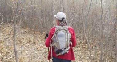 Zion Utah kışında kuru ormanda sırt çantasıyla gezen sağlıklı yaşlı bir kadın. Ölü yaprakların ve ağaçların arasında yürüyen mutlu bir kadın yürüyüşçü.