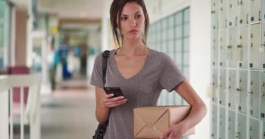 Posta kutularını postanenin koridorunda tutarken cep telefonu kullanan bir kadın. Milenyum kadını postanedeyken akıllı telefon uygulaması kullanarak paketi takip ediyor. 4k