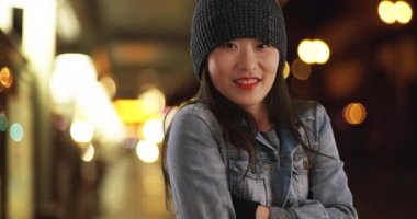 Donmuş milenyum kadını eldivenlerle ısınmaya çalışıyor ve metroda kollarını ovuşturuyor. Tren istasyonunda ısınmak için şapka ve eldiven takan Asyalı genç bir kadın. 4k