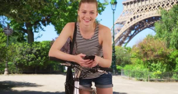 在巴黎用自行车和智能手机的千禧年女孩的画像 艾菲尔铁塔附近的白人女人对着摄像机笑 — 图库视频影像