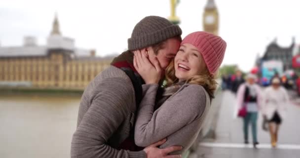 这对年轻夫妇在伦敦的户外笑容可亲的画像 快乐的白人男性和女性站在威斯敏斯特桥上相互凝视着对方的眼睛 — 图库视频影像