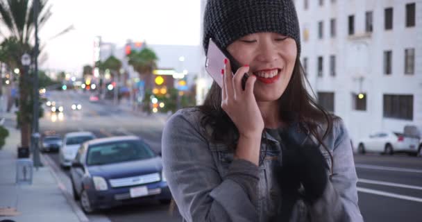 快乐的千禧年女性在长滩用手机聊天 尽量保暖 在南加州 快乐的年轻亚洲女人在智能手机上聊天 — 图库视频影像