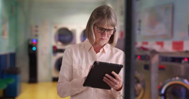 Unabhängige Seniorin Nutzt Tablet Gerät Waschsalon Online Surfen Reife Weiße — Stockvideo