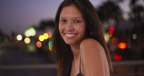 城市环境中美丽的白人女孩的衣服 灯火通明 20多岁的年轻貌美的女性回头望着 微笑着 — 图库视频影像