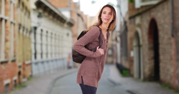 快乐的白人女人在布鲁日的一条小街上漫步 迷人的年轻女子背着背包站在室外 — 图库视频影像